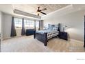 Cozy bedroom featuring large windows, tray ceiling and plush carpeting at 18690 W 84Th Dr, Arvada, CO 80007