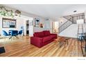 Open-concept living room with hardwood floors, a red sofa, and adjacent dining area at 2557 S Dover St # 30, Lakewood, CO 80227