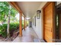 Inviting covered porch with natural wood pillars and views of the meticulously kept landscape at 290 Mohawk Dr, Boulder, CO 80303