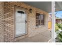 Covered front porch featuring brickwork, a white door, and a side window at 560 S 9Th St, Berthoud, CO 80513