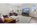 Bright living room with hardwood floors, large windows, comfortable seating, and a modern entertainment center at 6233 Easton Ave, Frederick, CO 80504