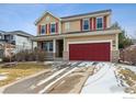 Inviting two-story home featuring a red two car garage, a covered porch and nicely kept landscaping at 13850 Meadowbrook Dr, Broomfield, CO 80020