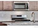 Close-up of stainless steel microwave and range with subway tile backsplash at 1419 Great Western Dr, Longmont, CO 80501