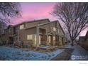 Charming townhouse featuring a covered porch, brick accents, and partial snow cover at 1601 Great Western Dr # 3, Longmont, CO 80501