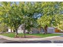 Well maintained corner lot home featuring mature trees, a green lawn, and gray siding at 2437 Maplewood E Cir, Longmont, CO 80503