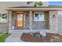 Close up of front door and porch featuring gray brick and unique dragon statuettes at 2437 Maplewood E Cir, Longmont, CO 80503