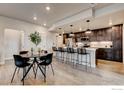 Bright, modern kitchen featuring wood floors, dark cabinets, a white countertop island, and barstool seating at 265 High Point Dr # 101, Longmont, CO 80504