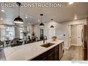 A kitchen island with a waterfall countertop and dark brown cabinetry with stainless steel appliances at 265 High Point Dr # 101, Longmont, CO 80504