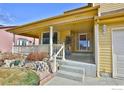 Welcoming covered front porch with white railings, stone accents, and a view of the neighborhood at 288 Dover Ct, Broomfield, CO 80020