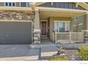 Close-up of front door and porch with a stone facade, and an inviting entrance with a decorative wreath at 458 Highlands Cir, Erie, CO 80516