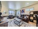 Open-concept living room featuring a comfortable leather sofa, large windows, and stylish decor at 1117 Hummingbird Cir, Longmont, CO 80501