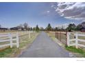 Long driveway leading to property with a white fence enclosing the premises at 3380 County Road 38, Mead, CO 80542