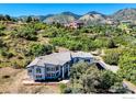 Scenic aerial view of the estate on a lush hillside with mountain backdrop at 5799 Crestbrook Cir, Morrison, CO 80465