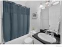 Cozy bathroom featuring a shower with a blue curtain, a toilet, and a sink with a black countertop at 887 Sundance Ln, Erie, CO 80516