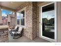 Relaxing covered front porch with rocking chairs and stone pillars and views of the neighborhood at 887 Sundance Ln, Erie, CO 80516