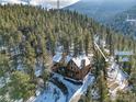 Aerial view of a mountain home in the forest, highlighting the home's setting at 1170 Elk Valley Dr, Evergreen, CO 80439