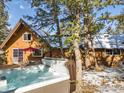 Inviting home exterior with a deck, hot tub, and outdoor seating, framed by towering evergreen trees at 1170 Elk Valley Dr, Evergreen, CO 80439