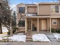 Charming townhouse exterior featuring a covered porch, welcome sign and snow-dusted landscaping at 1818 S Quebec Way # 3-1, Denver, CO 80231