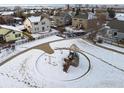 Snowy neighborhood park featuring a play structure, swings, and walking paths connecting to nearby homes at 2429 Tyrrhenian Dr, Longmont, CO 80504