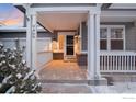 Inviting covered front porch with white columns and railings, leading to the main entrance of the home at 2429 Tyrrhenian Dr, Longmont, CO 80504