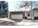 Charming home featuring a two-car garage with stone accents and a well-maintained front yard in a wintery landscape at 3025 Depo Dr, Longmont, CO 80503