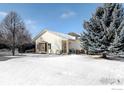 Well-maintained single-story home with a cozy front porch and snowy landscaping with mature trees at 3025 Depo Dr, Longmont, CO 80503