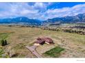 Expansive aerial view of a home with a two-car garage against a mountain backdrop under a partly cloudy blue sky at 4702 Eldorado Springs Dr, Boulder, CO 80303
