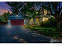 Charming two-story home featuring a well-maintained lawn and a spacious driveway leading to a red garage door at dusk at 510 Folklore Ave, Longmont, CO 80504