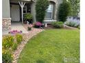 Well-manicured front yard with a stone pathway, vibrant flowerbeds, and lush green lawn enhance this home's curb appeal at 6242 Valley Vista Ave, Firestone, CO 80504