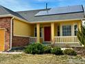 Home featuring a welcoming red front door, solar panels and lovely front yard landscaping at 6596 Silverleaf Ave, Firestone, CO 80504