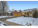 Street view of charming home with a brick facade, a two-car garage, a welcoming porch, and solar panels at 6596 Silverleaf Ave, Firestone, CO 80504