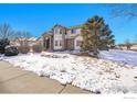 Inviting two-story home with stone accents, a well-maintained lawn and mature trees at 6943 Saddleback Ave, Firestone, CO 80504