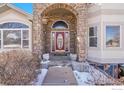 Elegant arched entryway with stone detailing and a stylish front door creating a welcoming entrance at 6943 Saddleback Ave, Firestone, CO 80504