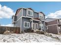 Stylish two-story townhome with blue siding, white trim, and red accents, surrounded by a snow-covered landscape at 711 Elm St, Frederick, CO 80530