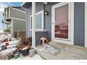 Charming front porch with blue siding, white trim, a window, and a glass front door, accented with potted plants at 711 Elm St, Frederick, CO 80530