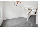 Bright living room featuring neutral carpet, white walls, a ceiling fan, and a staircase leading to the upper level at 711 Elm St, Frederick, CO 80530