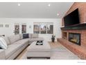 Cozy living room with a brick fireplace, plush seating, and natural light from the window at 7243 Siena Way, Boulder, CO 80301