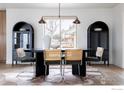 Well-lit dining room with a large window, modern light fixture, and wood flooring at 8309 W 69Th Way, Arvada, CO 80004