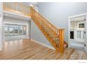 Inviting entryway with hardwood floors, wooden staircase and views of the front room fireplace at 8916 Prairie Knoll Dr, Longmont, CO 80503