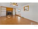 Living room features hardwood floors, a stone fireplace, and a ceiling fan at 9089 Vermillion Rd, Longmont, CO 80503