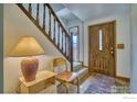 Inviting foyer with hardwood floors, a wooden staircase, and a stylish entry door at 106 Granada Ct, Longmont, CO 80504