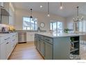 Well-lit kitchen with stainless steel appliances, large center island, and hardwood floors at 470 Muirfield Cir, Louisville, CO 80027