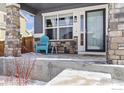 Inviting front porch featuring stone pillars, a blue Adirondack chair, and a view of the front yard at 490 N Ider Way, Aurora, CO 80018