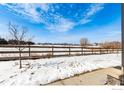 Serene backyard view with a wooden fence, snowy ground, and beautiful natural surroundings at 891 Winding Brook Dr, Berthoud, CO 80513