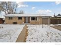 Charming brick ranch home with snowy front yard and walkway at 920 W 1St Ave, Broomfield, CO 80020