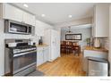 Open concept kitchen with stainless steel appliances, white cabinets, hardwood floors, and dining area at 920 W 1St Ave, Broomfield, CO 80020