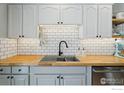 Close up of an updated kitchen with white subway tile, butcher block counters and black hardware at 920 W 1St Ave, Broomfield, CO 80020