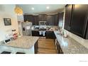 Well-lit kitchen featuring granite counters, stainless steel appliances, and dark wood cabinets at 14860 Guernsey Dr, Mead, CO 80542