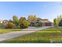 Spacious home with a circular driveway, lush lawn, mature trees, and beautiful blue accents at 1574 Carlson Ave, Erie, CO 80516