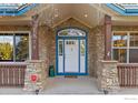 Charming home entrance with stone accents, blue trim, and a security system at 1574 Carlson Ave, Erie, CO 80516